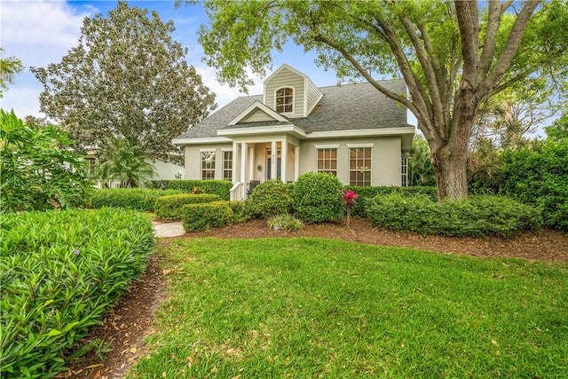 new england style home with a shingled roof, a front lawn, and stucco siding