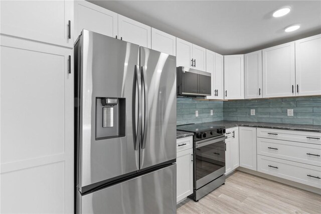 12 Plantation Dr Unit 104, Vero Beach, FL 32966 - kitchen with appliances with stainless steel finishes, dark stone counters, white cabinetry, backsplash, and light wood-type flooring