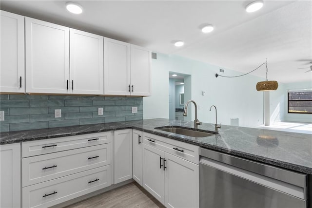 12 Plantation Dr Unit 104, Vero Beach, FL 32966 - kitchen featuring dishwasher, a sink, white cabinets, backsplash, and dark stone counters