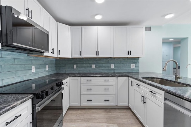 12 Plantation Dr Unit 104, Vero Beach, FL 32966 - kitchen featuring stainless steel appliances, a sink, white cabinets, dark stone counters, and tasteful backsplash