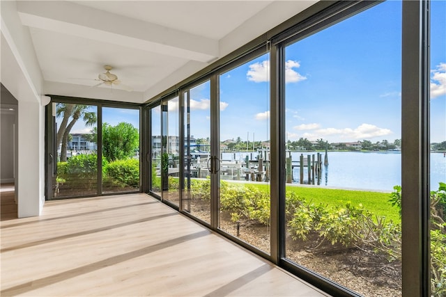 unfurnished sunroom featuring plenty of natural light, ceiling fan, and a water view