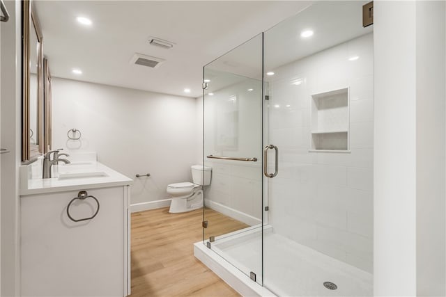 bathroom featuring hardwood / wood-style flooring, vanity, an enclosed shower, and toilet