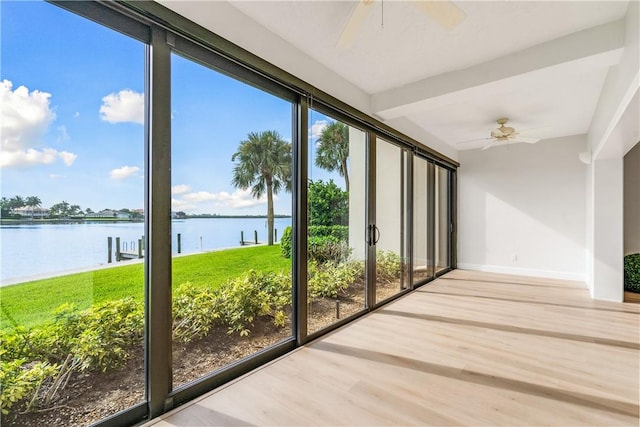 unfurnished sunroom featuring ceiling fan, a healthy amount of sunlight, and a water view