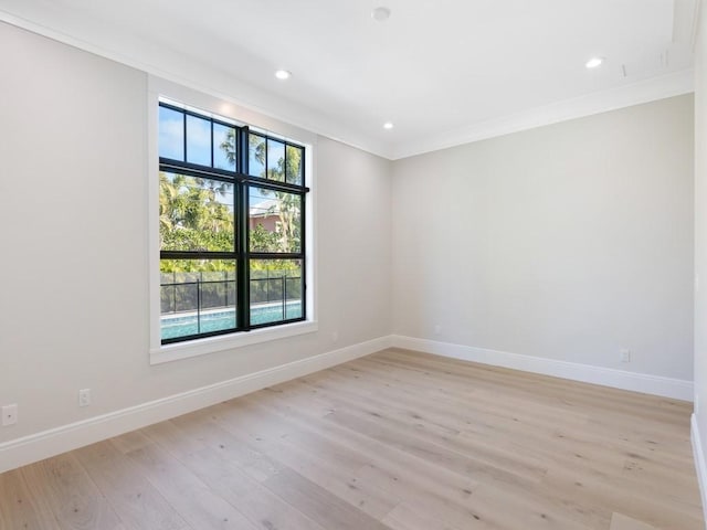 spare room featuring light wood-type flooring and crown molding