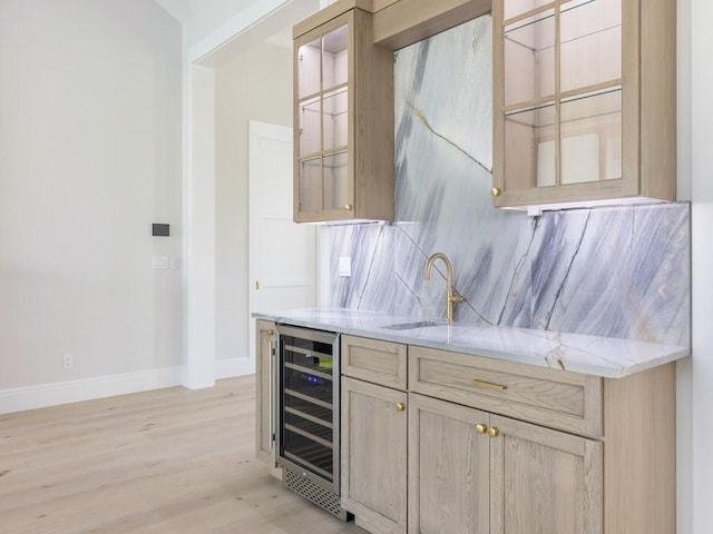 bar featuring light stone countertops, sink, light wood-type flooring, wine cooler, and light brown cabinets