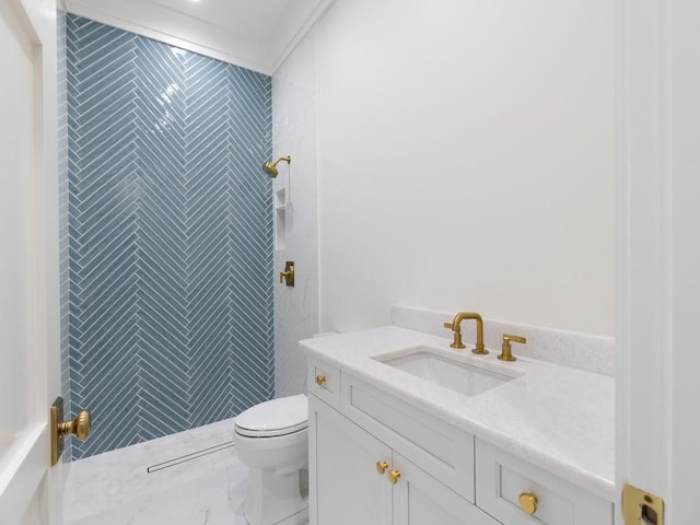 bathroom with toilet, a tile shower, and vanity