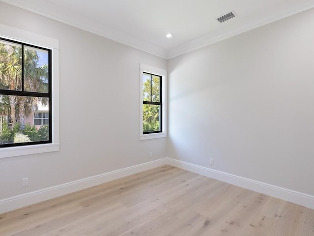 spare room with plenty of natural light, crown molding, and light hardwood / wood-style flooring