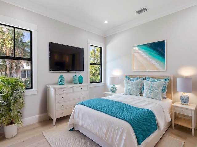 bedroom featuring ornamental molding, multiple windows, and light wood-type flooring