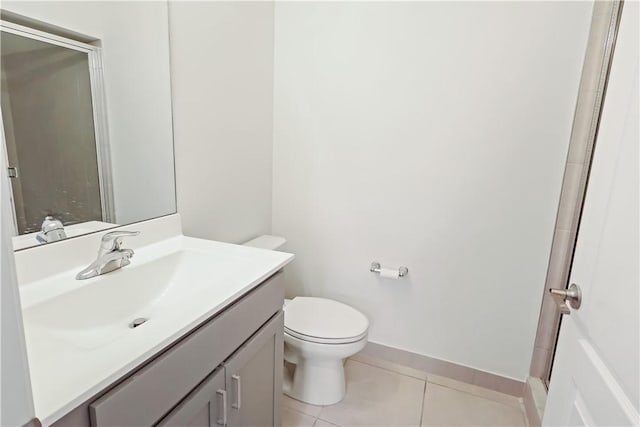 bathroom featuring a shower with door, toilet, vanity, baseboards, and tile patterned floors