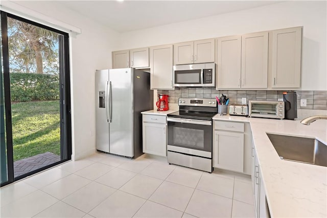 kitchen with stainless steel appliances, a toaster, a sink, and decorative backsplash