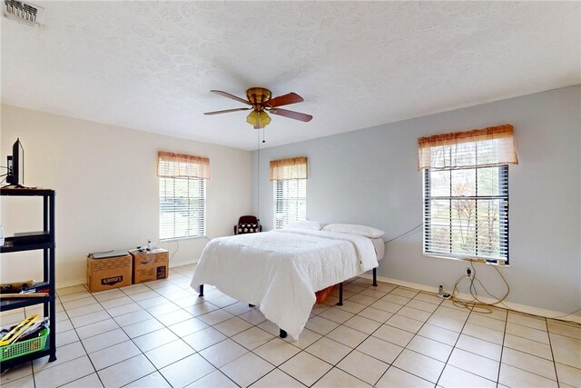 bedroom featuring visible vents, ceiling fan, a textured ceiling, and light tile patterned floors