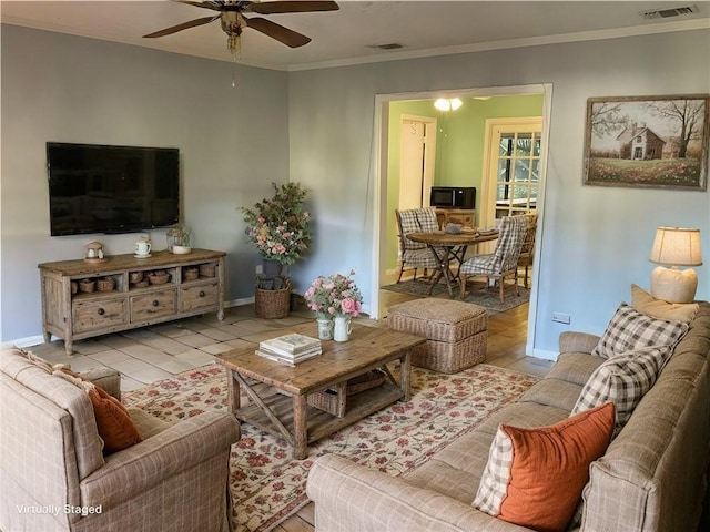 living room featuring ornamental molding, visible vents, baseboards, and wood finished floors