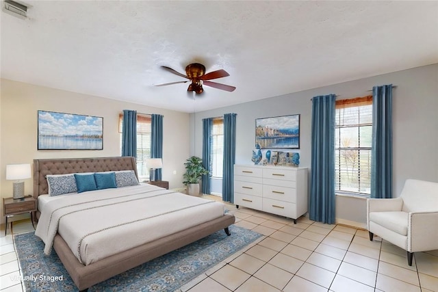 bedroom with baseboards, visible vents, a ceiling fan, and light tile patterned flooring