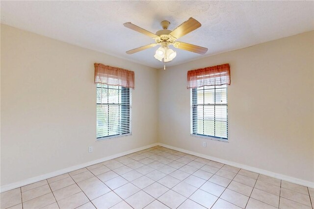 empty room featuring plenty of natural light, a textured ceiling, baseboards, and ceiling fan