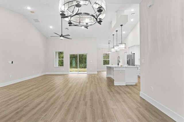 unfurnished living room with a raised ceiling, ceiling fan, sink, and dark hardwood / wood-style floors