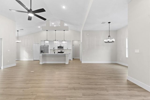 unfurnished living room with vaulted ceiling, sink, ceiling fan with notable chandelier, and light hardwood / wood-style flooring