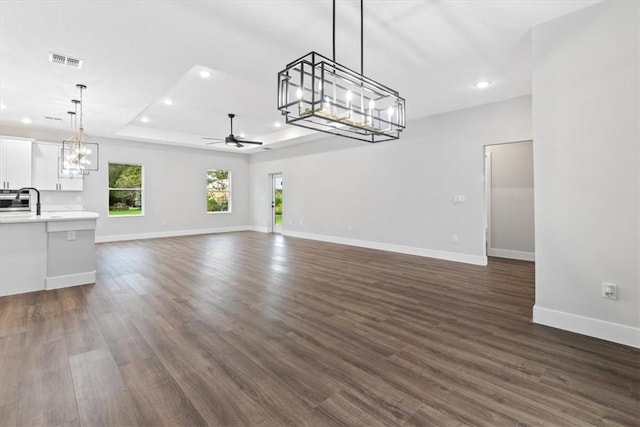 unfurnished living room with dark hardwood / wood-style floors, a raised ceiling, ceiling fan, and sink