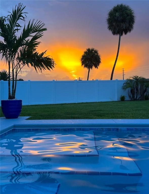 view of pool with fence and a lawn