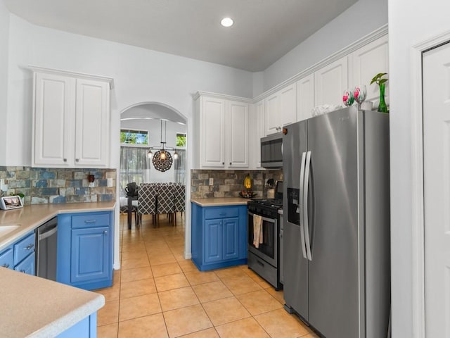 kitchen with white cabinets, blue cabinets, arched walkways, and appliances with stainless steel finishes