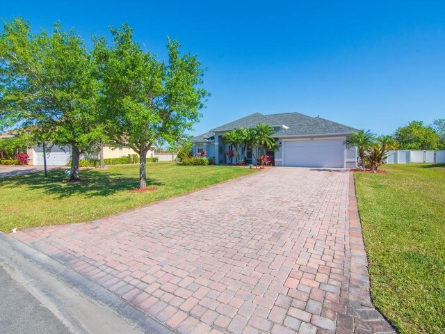 ranch-style home featuring a front lawn, decorative driveway, fence, and a garage