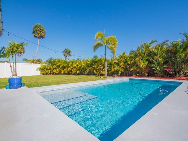 view of swimming pool featuring a patio, a yard, fence, and a fenced in pool