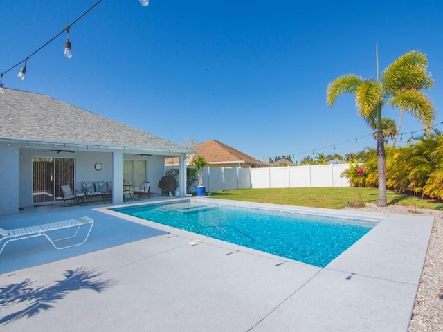 view of swimming pool featuring a lawn, a patio, fence, a fenced in pool, and ceiling fan