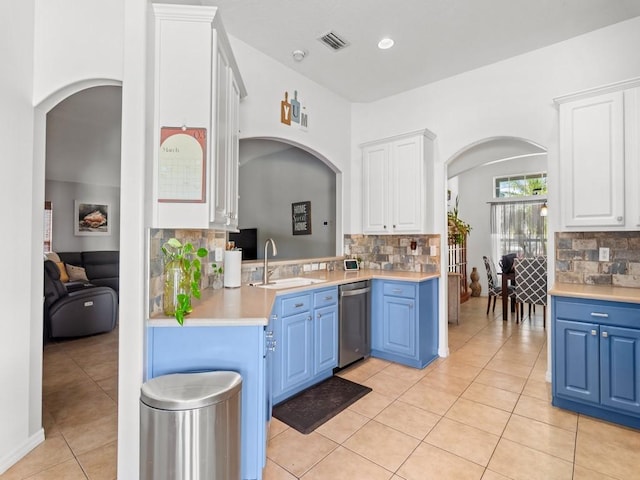 kitchen featuring visible vents, blue cabinetry, a sink, arched walkways, and stainless steel dishwasher