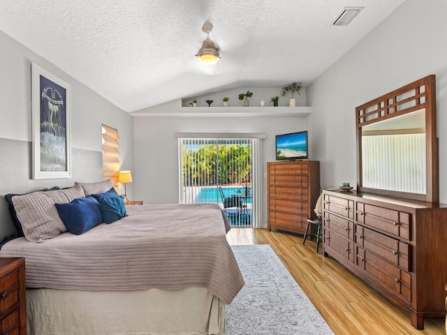 bedroom with access to exterior, vaulted ceiling, light wood-type flooring, and a textured ceiling