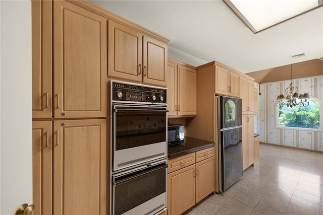 kitchen featuring wallpapered walls, baseboards, light brown cabinetry, black appliances, and a notable chandelier