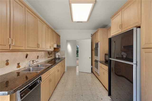 kitchen featuring dark countertops, a sink, light brown cabinetry, black appliances, and backsplash