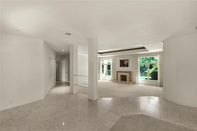 interior space featuring decorative columns, visible vents, and a fireplace with raised hearth