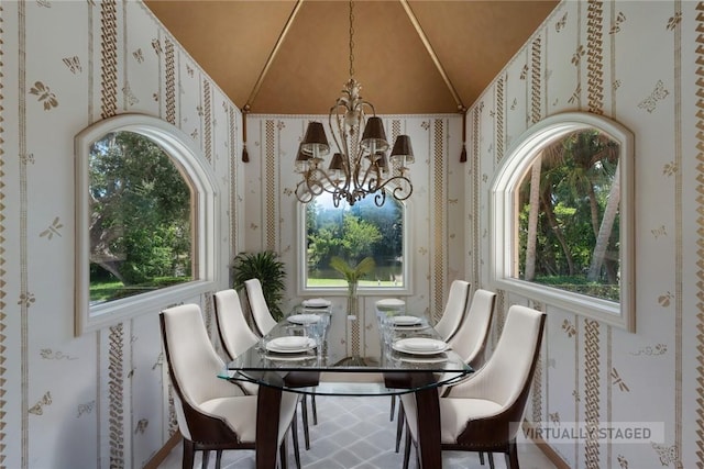 dining space featuring lofted ceiling, a healthy amount of sunlight, and a chandelier