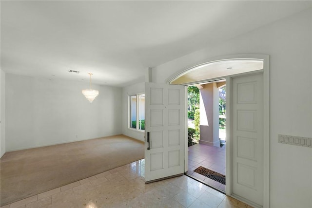 foyer entrance with light tile patterned floors, light colored carpet, visible vents, a chandelier, and baseboards