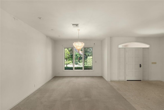 spare room featuring light carpet, an inviting chandelier, and visible vents