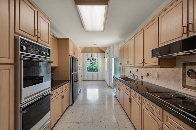 kitchen featuring dark countertops, a sink, black appliances, light brown cabinets, and backsplash