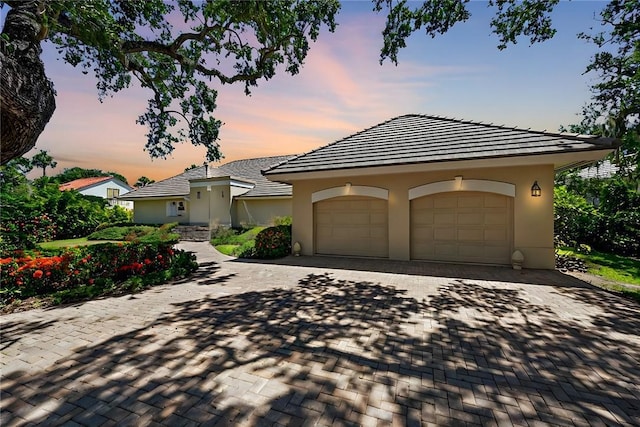 view of front of home with a garage, decorative driveway, and stucco siding