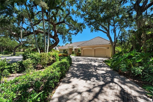 view of front of property featuring a garage, decorative driveway, and stucco siding