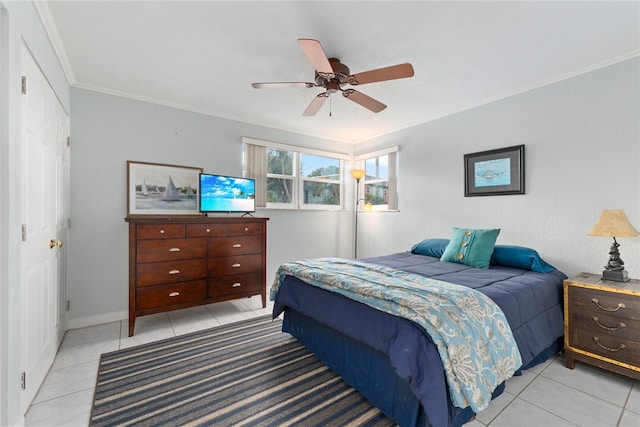 bedroom with light tile patterned flooring, ceiling fan, a closet, and crown molding