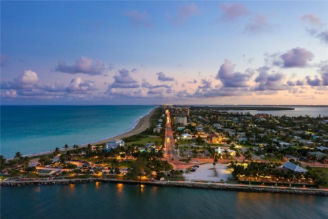 aerial view at dusk with a water view and a view of the beach