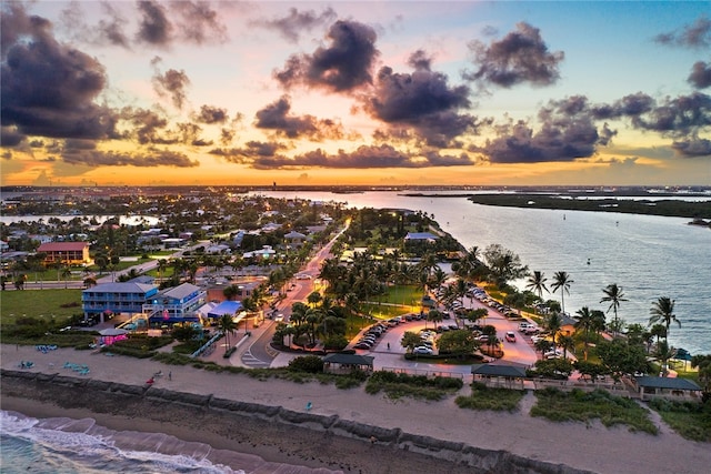 aerial view at dusk with a view of the beach and a water view