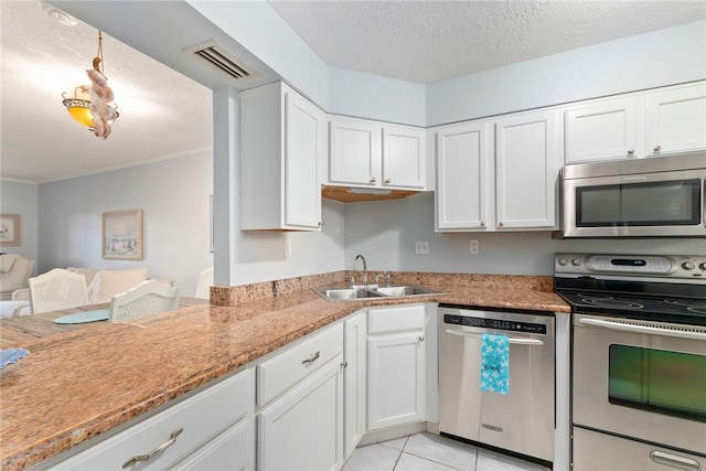 kitchen with light tile patterned flooring, sink, appliances with stainless steel finishes, a textured ceiling, and white cabinets