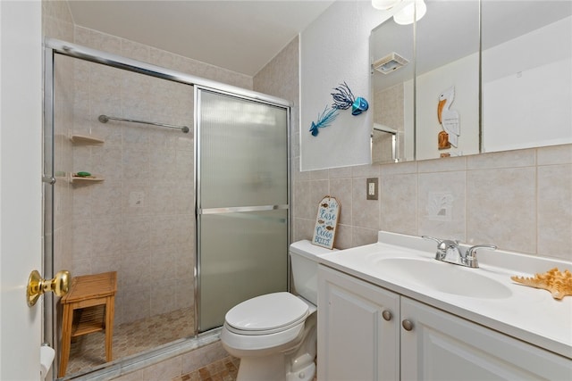 bathroom featuring tile walls, tile patterned floors, walk in shower, vanity, and toilet