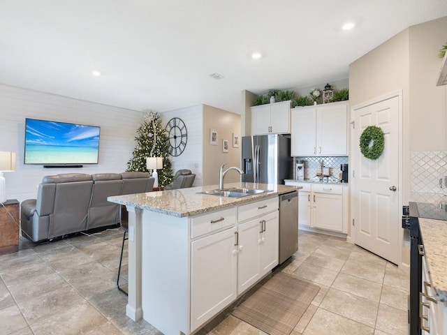 kitchen with sink, tasteful backsplash, a kitchen island with sink, white cabinets, and appliances with stainless steel finishes