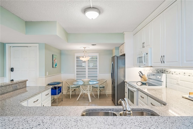 kitchen featuring white cabinets, a textured ceiling, white appliances, and sink