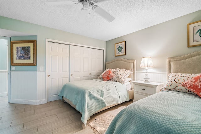 bedroom featuring a textured ceiling, light hardwood / wood-style flooring, ceiling fan, and a closet