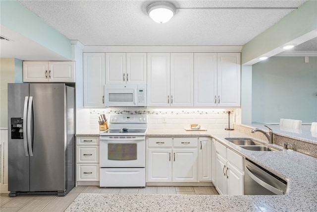 kitchen with a textured ceiling, sink, backsplash, white cabinetry, and appliances with stainless steel finishes