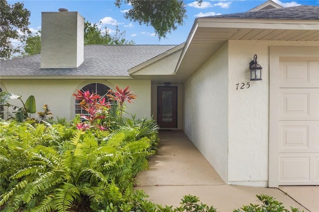 725 Wentworth St, Sebastian, FL 32958 - entrance to property featuring a shingled roof, stucco siding, a chimney, and an attached garage