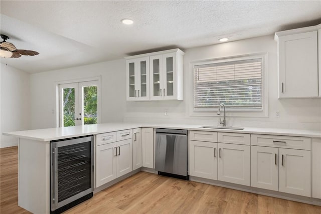 725 Wentworth St, Sebastian, FL 32958 - kitchen with beverage cooler, stainless steel dishwasher, a sink, a peninsula, and white cabinetry