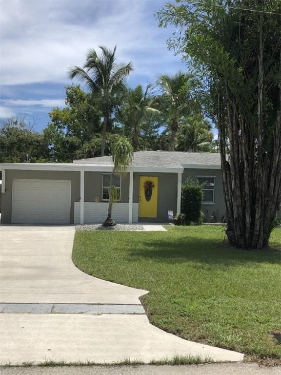 ranch-style house with a front lawn, driveway, a garage, and stucco siding