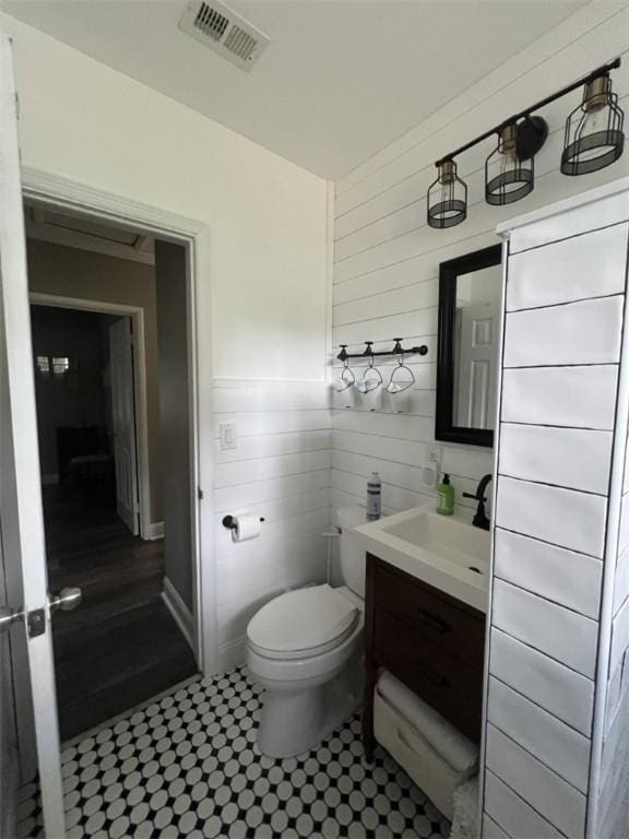 half bathroom with toilet, vanity, and tile patterned flooring